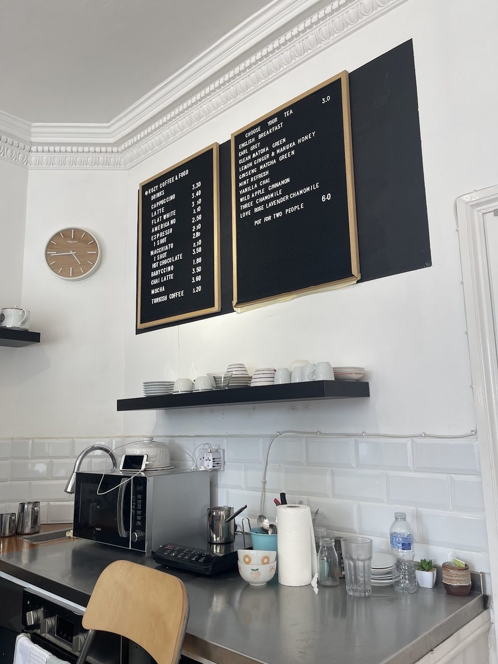 The espresso machine and prep station with a shelf of cups above