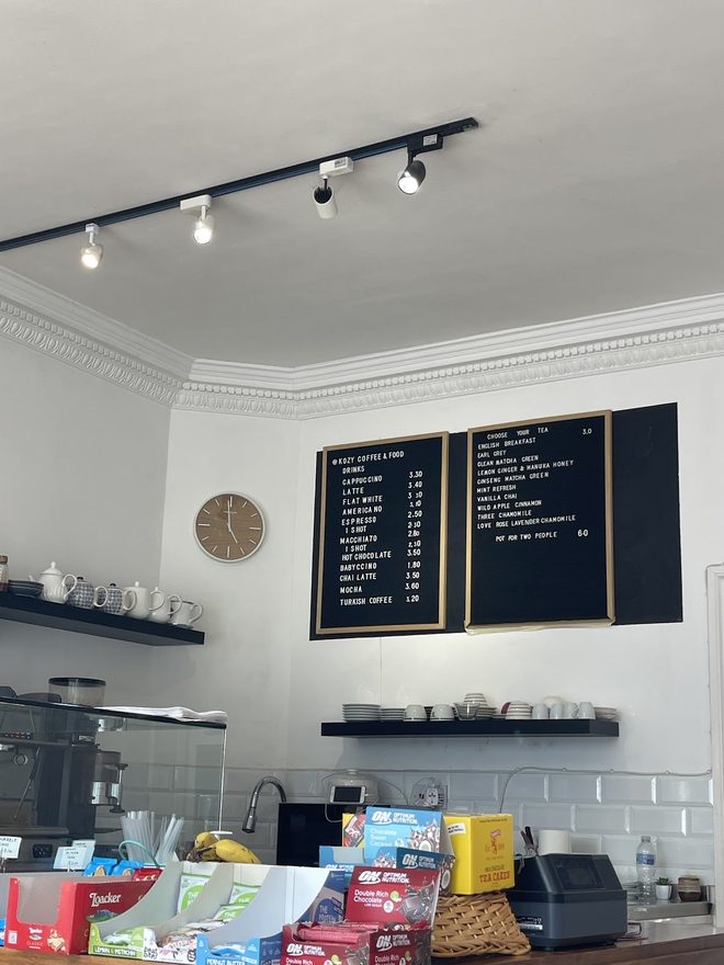 Interior corner with track lighting, shelved crockery and the till end of the counter