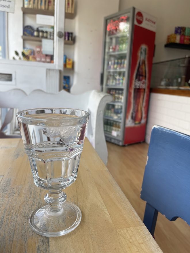 A footed dessert glass on a wooden table, the counter soft behind