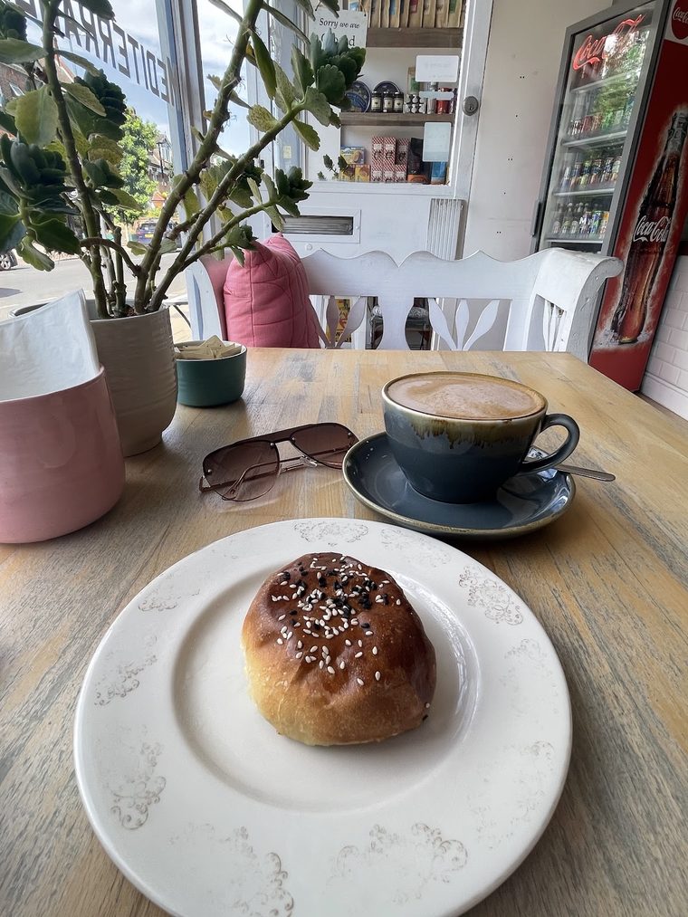 Cinnamon bun and cappuccino on a wooden window table